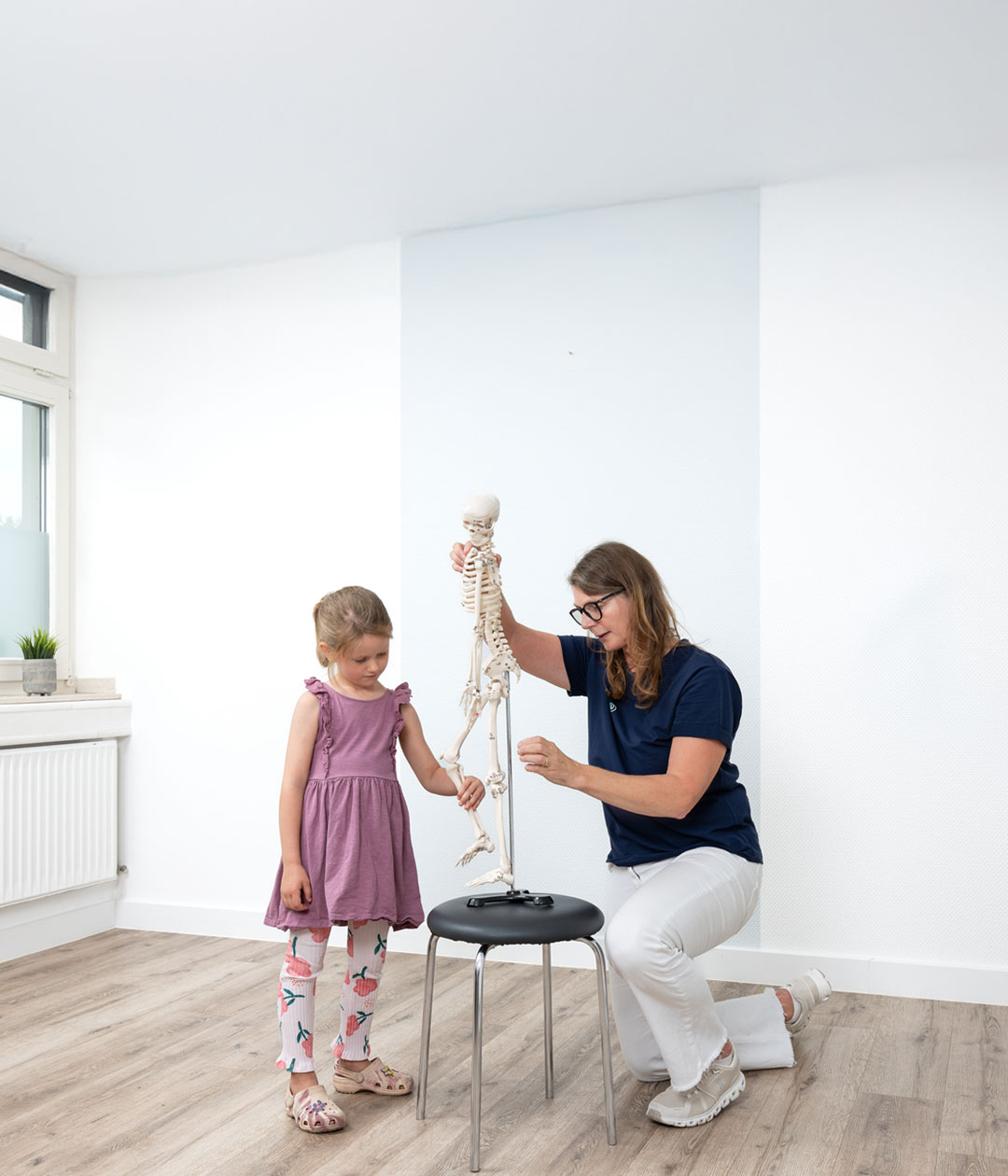 Dr. med. Claudia Müller-Gliemann erklärt einem Kind das menschliche Skelett in der Praxis Orthopädie am Grünewald