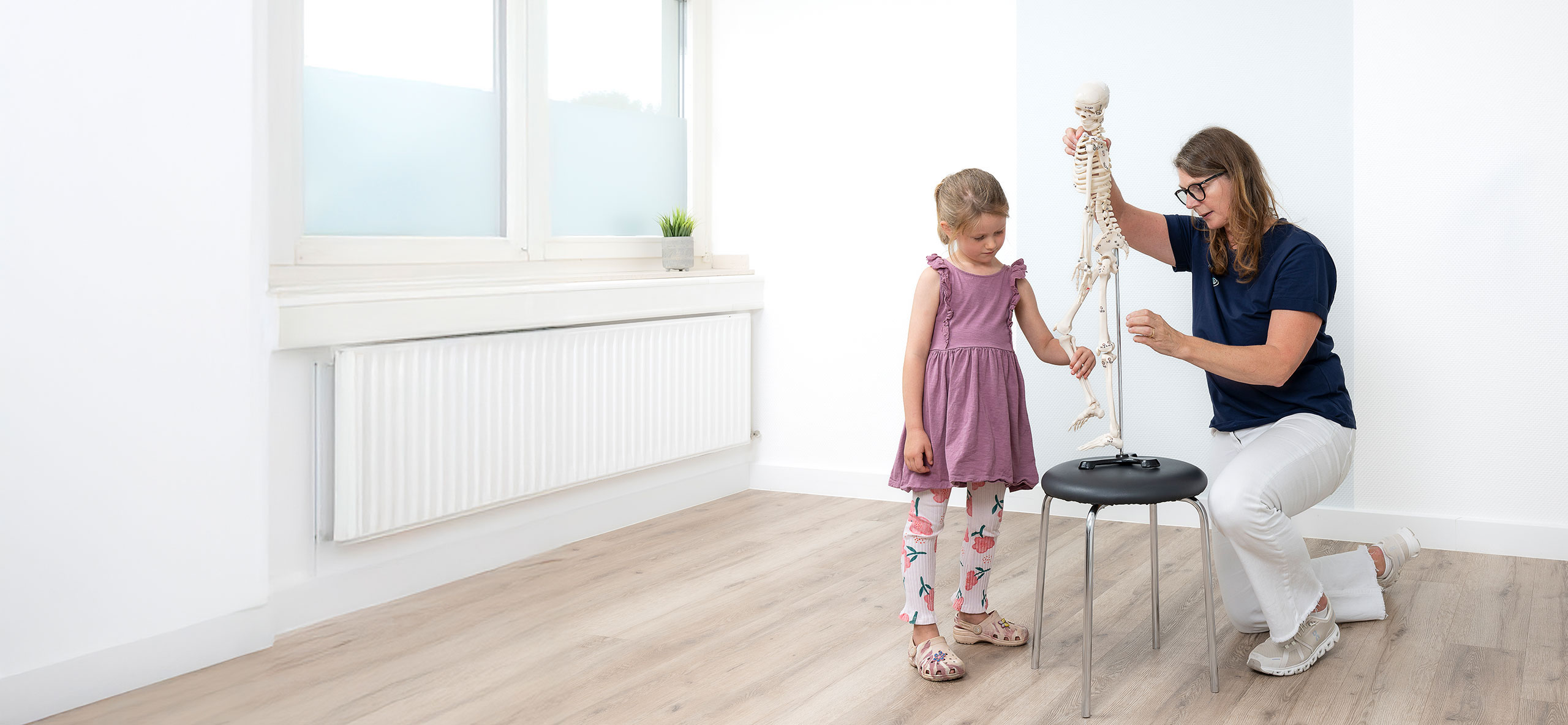 Dr. med. Claudia Müller-Gliemann erklärt einem Kind das menschliche Skelett in der Praxis Orthopädie am Grünewald