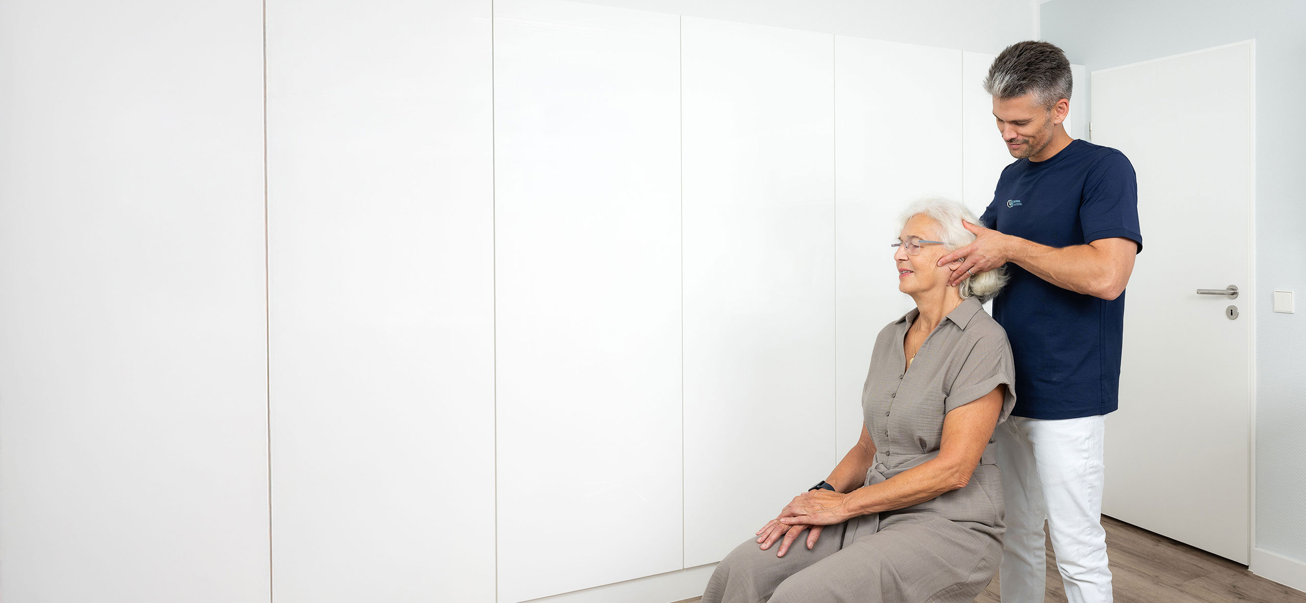 Korbinian Lenz bei der manualmedizinischen Untersuchung einer älteren Patientin in der Praxis Orthopädie am Grünewald